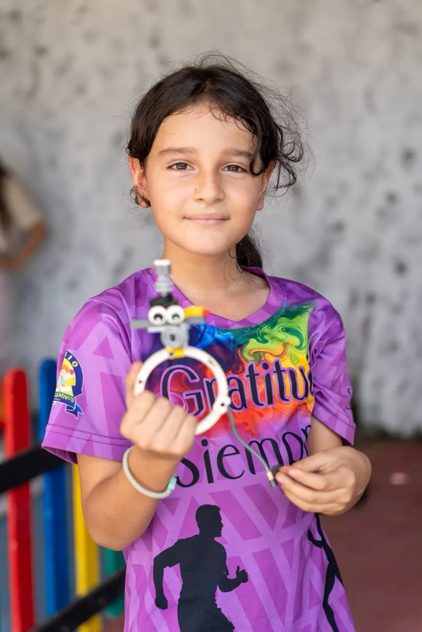 Niña sostiene el robot que construyó