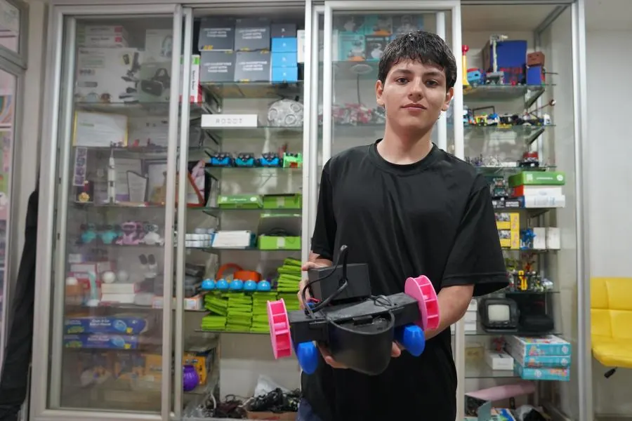 Juan Esteban Gómez sostiene el barco robot Wept Life frente a las vitrinas de ScienceBot